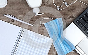 Hygiene in the office. remote work kit on wooden desk. sanitizer gel and face mask photo