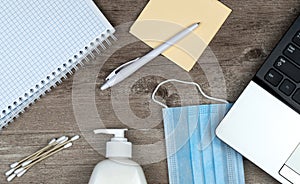 Hygiene in the office. Top view office desk, desktop with laptop, phone and medical face mask