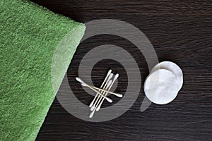 Hygiene supplies, cotton sticks and cotton swabs near a white towel on a blue background.