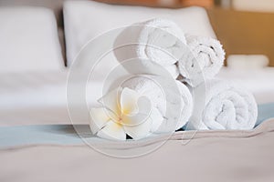 Hygiene white rolled towel and blooming plumeria flower  on  bed in bedroom