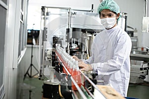 Hygiene worker working in drink factory at conveyor belt with fruit juice glass bottled in production line