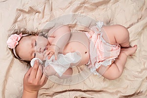 Hygiene - young mom wiping the baby skin body and face with wet wipes carefully on pink background. concept cleaning