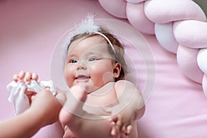 Hygiene - young mom wiping the baby skin body and face with wet wipes carefully on pink background. concept cleaning wipe, pure,