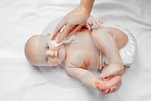 Hygiene - young mom wiping the baby skin body and face with wet wipes carefully on white background. concept cleaning wipe, pure,