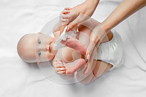 Hygiene - young mom wiping the baby skin body and leg with wet wipes carefully on white background. concept cleaning wipe, pure,