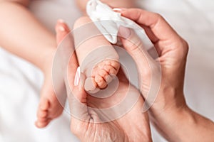 Hygiene - young mom wiping the baby skin body with wet wipes carefully. Mother changing the baby nappy in nursery. concept