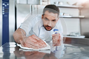 Hygienic precautions. Worker in restaurant kitchen cleaning down after service. Selective focus on his hand