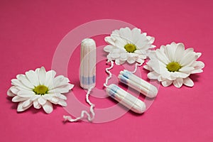 Hygienic tampons on a pink background with white flowers