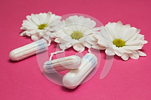 Hygienic tampons and white flowers on a pink background