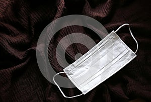Hygienic white face mask for protect Covid 19 on dark brown background
