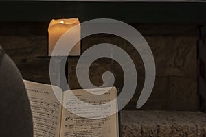 Hymnal illuminated by candle flame in a church