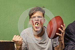 Hyped kid with mouth full of popcorn american football