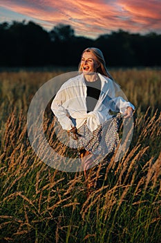 Hyped young blond woman looking afar, running through a wheat field.