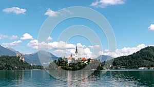 Hyper lapse of Bled Island with church of the Assumption of Mary and Bled castle on Lake Bled at clear summer day. Travel and adve