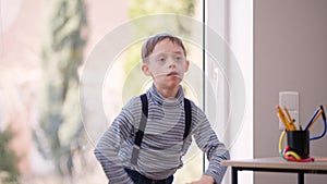 Hyperactive autistic boy jumping gesturing indoors laughing having fun. Portrait of cheerful happy Caucasian child with