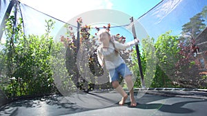 Hyperactive girl acrobatic jumping on outdoor trampoline. Handheld shot.