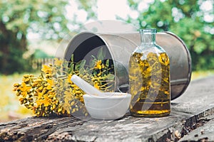 Hypericum - St Johns wort flowers, oil or infusion bottle, mortar and big vintage metal mug of Hypericum flowers.