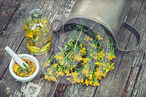 Hypericum - St Johns wort plants, oil or infusion bottle, mortar on wooden board.