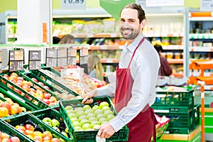 Hypermarket clerk filling up storage racks