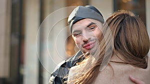 Hypocritical gay man hugging friend rolling eyes smiling. Portrait of insincere young Caucasian LGBTQ person meeting