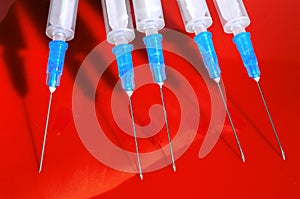 Hypodermic syringe. Syringes with blue needles on a red background. Medical Injectors.