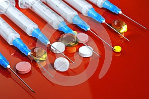 Hypodermic syringe. Syringes with blue needles on a red background. Medical Injectors.