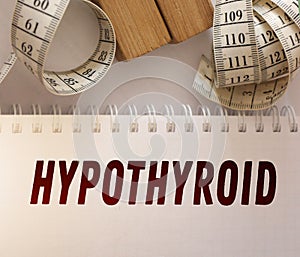 Hypothyroid word on page of copybook and measurement tape besides. Thyroid hormane causes overweight. Healthcare concept photo