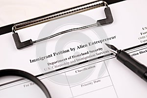 I-526 Immigrant Petition by Alien Entrepreneur blank form on A4 tablet lies on office table with pen and magnifying