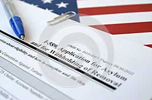 I-589 Application for asylum and for withholding of removal blank form lies on United States flag with blue pen from Department of