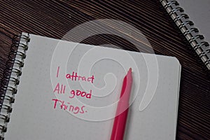 I Attract All Good Things write on a book on wooden table