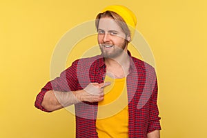 I am best! Self-confident egoistic guy in beanie hat and checkered shirt pointing himself, looking at camera