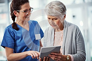 I can access it all from here. a young female nurse and her senior patient looking at a tablet in the old age home.