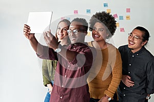 I can already picture all of us succeeding. a group of young businesspeople taking selfies together with a digital