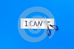 I can concept. Motivate youself, believe in yourself. Sciccors cut the letter t of written word I can`t. Blue background