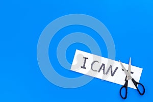 I can concept. Motivate youself, believe in yourself. Sciccors cut the letter t of written word I can`t. Blue background