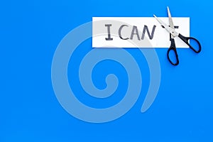 I can concept. Motivate youself, believe in yourself. Sciccors cut the letter t of written word I can`t. Blue background
