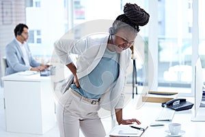 I can feel the long hours catching up to me. a young call centre agent experiencing back pain while working in an office