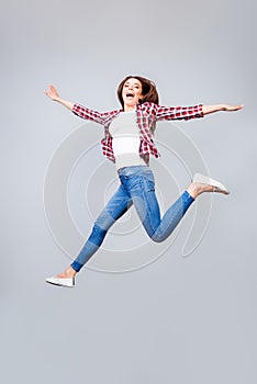 I can fly! Happiness, dream, fun, joy concept. Very excited happy cute brunette girl is jumping up, wearing casual clothes, white