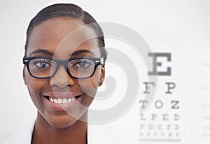 I can see clearly now. Portrait of a female optometrist standing beside a eye test chart.