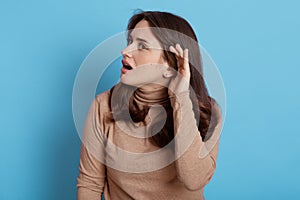 I can`t hear you! Confused woman keeping hand near ear to listen better, having hearing problems, difficult to understand, female