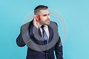 I can't hear you. Portrait of nosy brunette man with beard in suit trying to hear gossip, holding