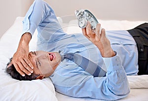 I cant believe I have to get up. A businessman looking at his alarm clock in disgust.