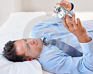 I cant believe thats the time already. A businessman looking at his alarm clock in disgust.