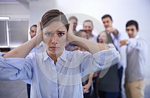 I cant hear you. a stressed young woman trying to block out her coworkers taunts.