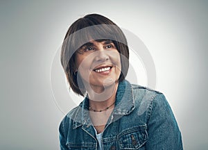 I cant help but wonder... Studio shot of a senior woman looking thoughtful against a grey background.