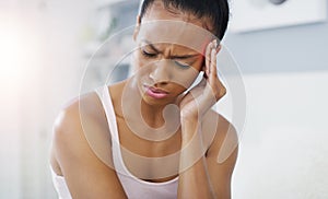 i cant manage to shake iff this headache. an attractive young woman suffering from a headache in her bedroom at home.