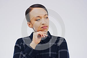 I cant stop thinking about it. Studio shot of a young woman looking thoughtful against a gray background.