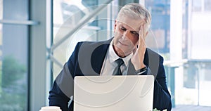 I cant think straight with this headache. a mature businessman looking stressed out while working in an office.