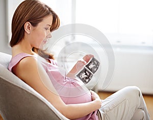 I cant wait to meet you...A beautiful pregnant woman looking at ultrasound scans of her baby - Copyspace.