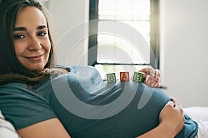 I cant wait to play with my little one. a young woman with baby blocks on her pregnant belly.